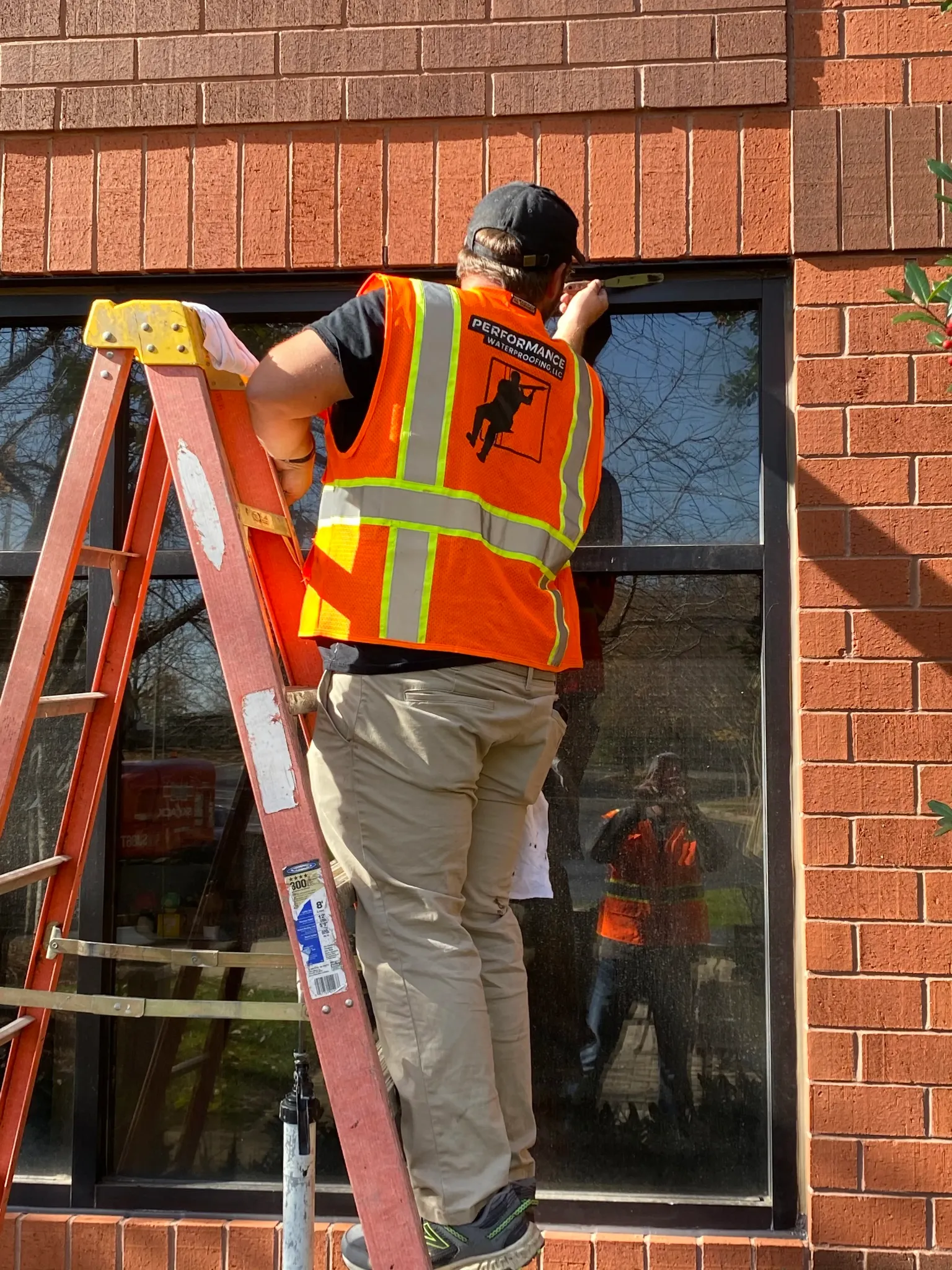 Worker applying sealant around a commercial building window